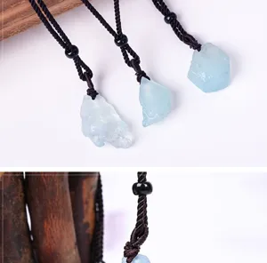 Vue détaillée du pendentif en pierre brute de cristal d'aigue-marine naturelle avec cordon noir.