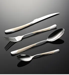Dettaglio posate in acciaio inossidabile, set da 4 pezzi con eleganti manici strutturati dorati.