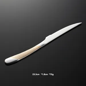 Dettaglio del coltello da bistecca in acciaio inox con manico a nido d'ape dorato e lama.