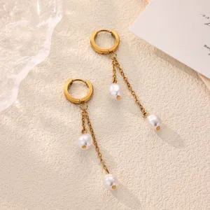 Detail closeup view of gold-plated stainless steel hoop earrings featuring pearl tassels.