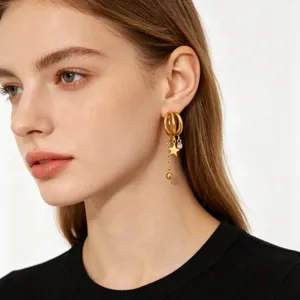 Close-up detail of multi-layer gold hoop earrings with star charms and sparkling crystal.