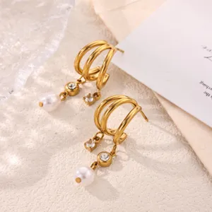Gold multi-layer C-hoop earrings featuring dangling pearls and sparkling crystal stones detail view.