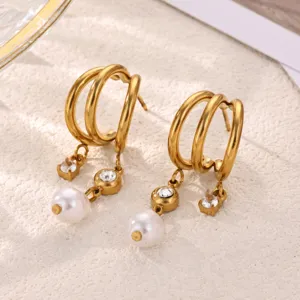 Close-up detail of multi-layer gold hoop earrings with faux pearl and crystal drops.