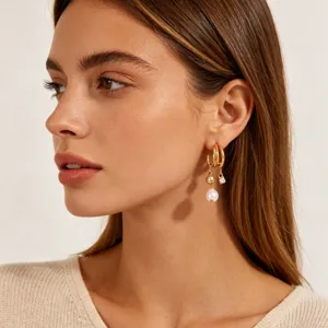 Close-up detail of multi-layer C-shaped gold-plated tassel earrings with pearl and stone.