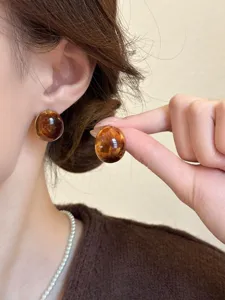 Detailed close-up view of retro amber round stud earrings worn by model, showing glossy texture.