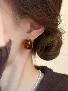 Amber resin stud earrings close-up detail, elegant retro style jewelry worn on ear.