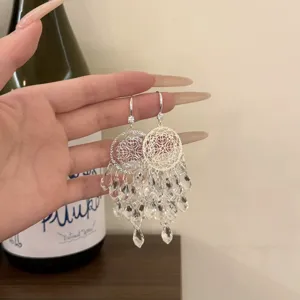 Close-up detail of silver dreamcatcher dangle earrings with sparkling crystal fringe beads.