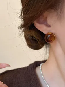 Close-up detail shot of vintage amber round stud earrings showing glossy texture and rich color.