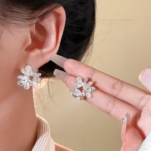 Detailed closeup of sparkling zircon flower stud earrings with shimmering shattered texture.