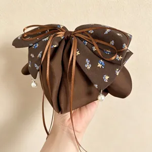 Braune florale Haarschleife mit Band und Perlenanhänger für elegante Retro-Frisuren.