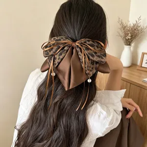 Detailansicht der Leopardenmuster-Stoffschleife mit Perlenhängern für halboffene Haare.
