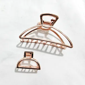 Dettaglio del set di pinze per capelli in metallo oro rosa con arco geometrico e mezzo cerchio.