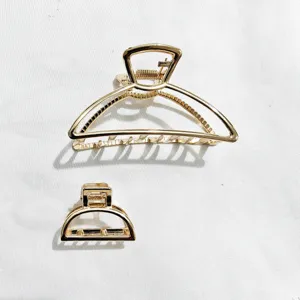 Primo piano dettagliato di mollette per capelli in metallo dorato, design geometrico elegante.