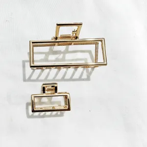 Molle per capelli rettangolari dorate in dettaglio, design metallico geometrico.