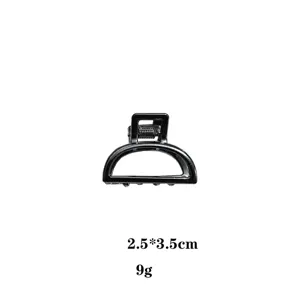 Vista dettagliata di una clip per capelli in metallo nero, con il suo design semicircolare.