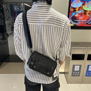 Vista di dettaglio della borsa a tracolla da uomo in pelle nera, stile casual urbano.