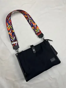 Detailed view of black nylon crossbody bag with colorful geometric strap and sturdy hardware.