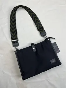 Detail view of black nylon messenger bag featuring adjustable green patterned shoulder strap.