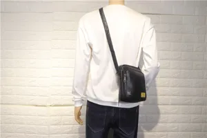 Detail view of black vertical messenger bag worn on shoulder, durable leather daily use.