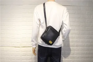 Black vertical crossbody messenger bag for men, durable leather material with adjustable strap.
