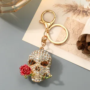 Glitzernder Strass Totenkopf Schlüsselanhänger mit roter Rose, goldenes Design für Taschen.