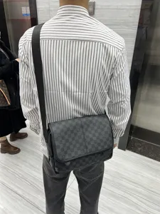 Sac à bandoulière pour homme à carreaux noirs porté au dos style décontracté vue arrière.