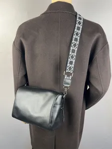 Vue détaillée sac bandoulière homme en cuir souple avec sangle large motif et quincaillerie.