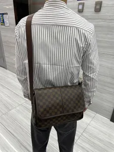 Vue détaillée du sac bandoulière à motif damier marron porté au dos avec sangle.