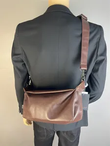 Details of the retro brown leather messenger bag with wide strap, worn on shoulder for men.