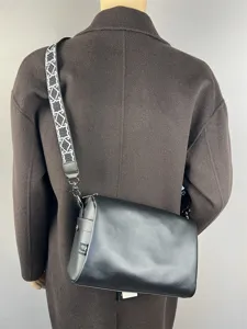 Vue détaillée du sac bandoulière en cuir noir avec une large sangle à motif géométrique.