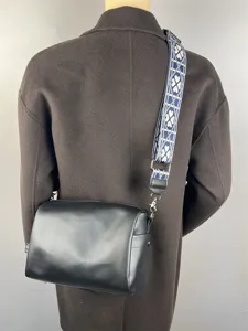 Élégant sac bandoulière noir en cuir synthétique avec une large sangle à motif de trèfle bleu.