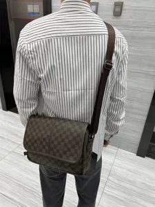 Vue détaillée du sac bandoulière à carreau marron pour homme, style rétro élégant.