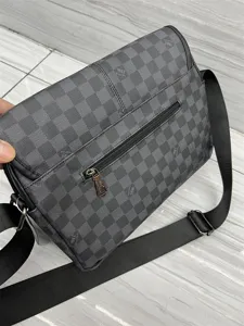 Sac bandoulière à carreaux gris pour homme avec sangle réglable et poche zippée au dos.
