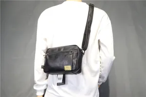 Detail shot showing the black soft leather cross-body bag worn on shoulder with zipper pocket.
