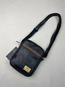 Detailed view of black vertical crossbody bag, PU leather texture with brown stripe.