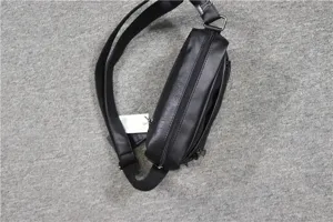 Detail view of black PU leather sling bag showcasing adjustable strap and front zipper pocket.