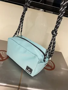 Detailed view of casual canvas crossbody bag with thick black white rope straps and blue color.