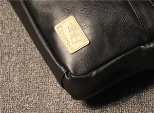 Detailed close-up view of the black leather shoulder bag corner showing brand logo patch.