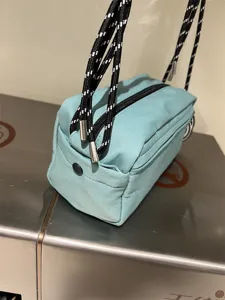 Canvas crossbody bag detail showing mint green fabric and black white rope strap.