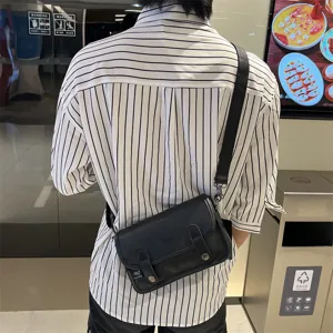 Dettaglio in primo piano della borsa a tracolla in pelle nera, design vintage con patta.