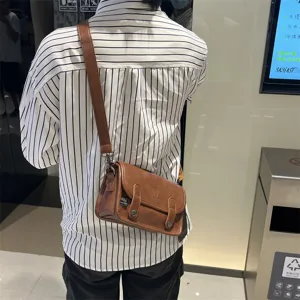 Dettaglio borsa a tracolla vintage marrone da uomo, borsa messenger retro con patta e cinta.