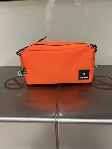 Orange canvas crossbody bag detail, casual small shoulder bag with black strap and logo patch.