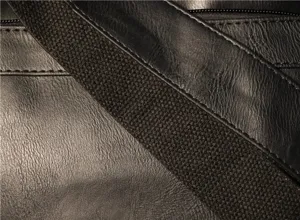 Close-up detail of black faux leather men shoulder bag with woven strap and zipper, stylish.