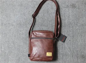 Detailed view of brown leather men's vertical shoulder bag, featuring soft texture and zipper.