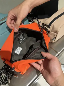Orange canvas crossbody bag interior detail showing inner pockets and label structure.