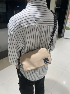 Canvas cross body bag detail view, on model wearing khaki small sling bag with strap.