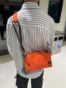 Detailed view of casual orange canvas crossbody bag for men and women, stylish daily commute.