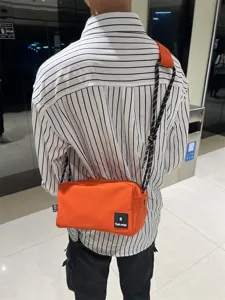 Trendy bright orange canvas crossbody bag for men and women, stylish casual shoulder bag.