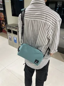 Detail view of teal canvas crossbody bag with black rope strap, casual commuting style.