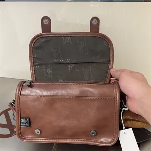 Dettaglio borsa a tracolla in pelle PU marrone, patta aperta con fodera e chiusure magnetiche.